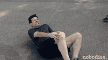 Gif of Jason Bateman in Nobodies on the ground holding a hurt knee