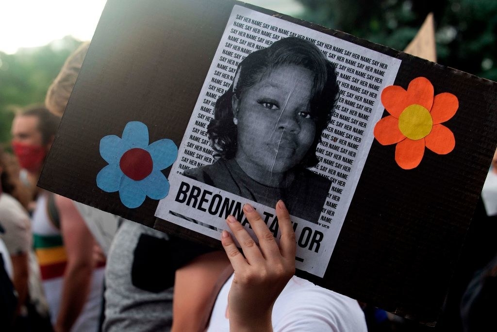 A protestor holding a sign with Breonna Taylor&#x27;s picture