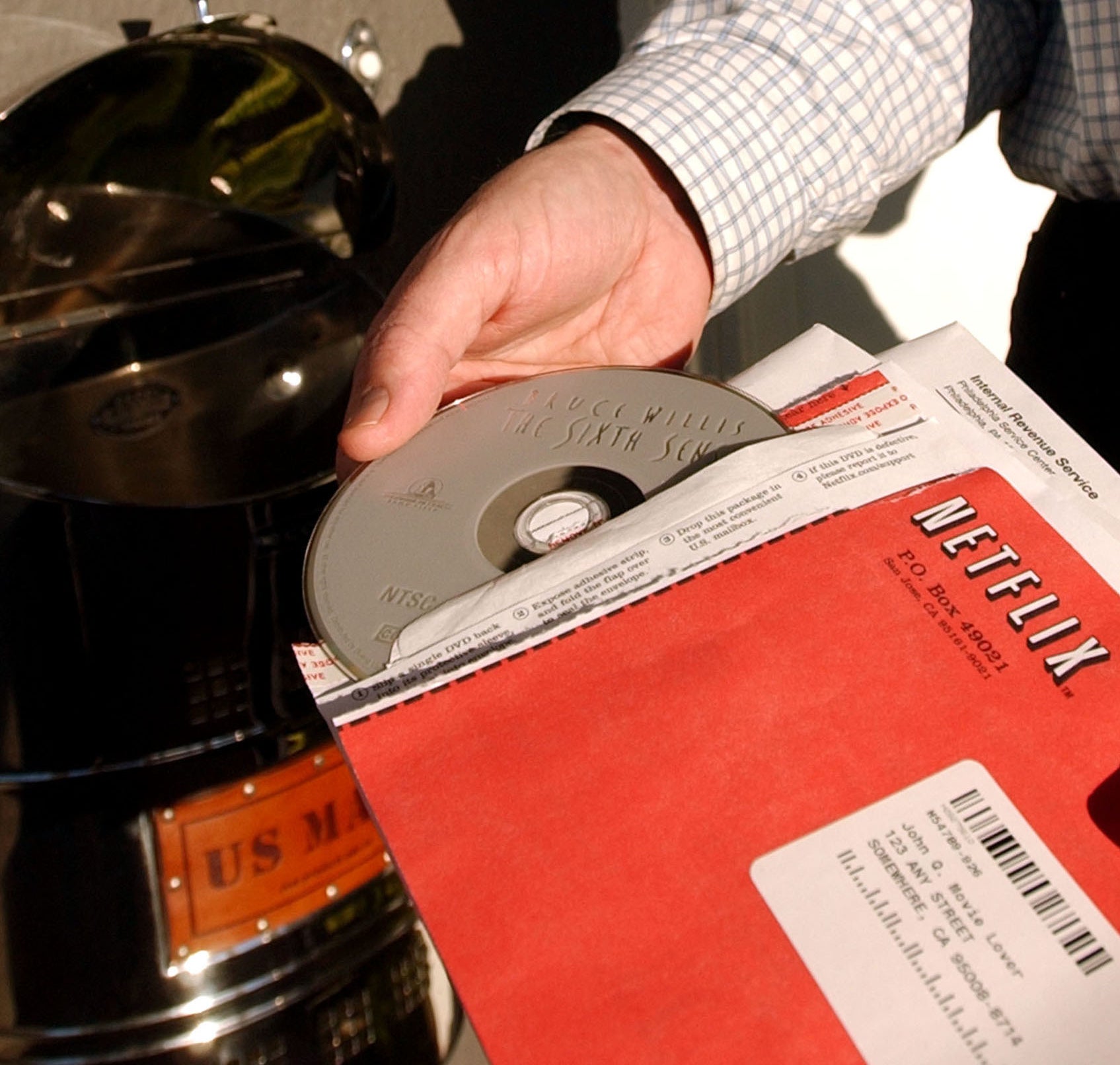 A photo of a man pulling a &quot;The Sixth Sense&quot; out a red Netflix envelope 