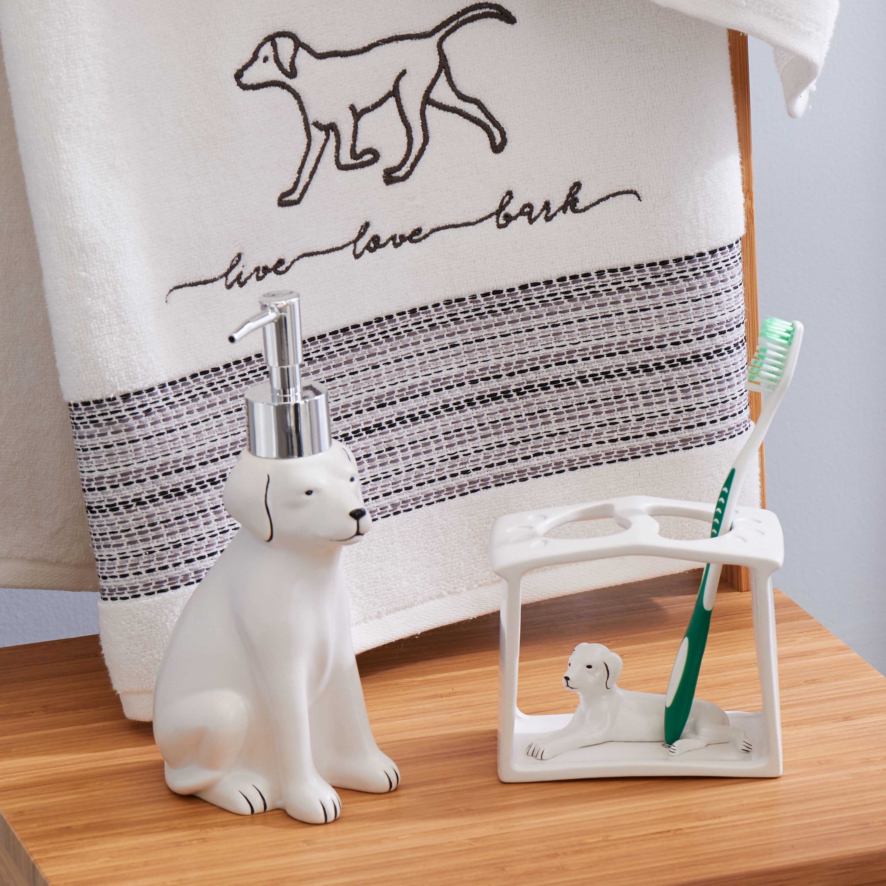 A soap dispenser in the shape of a white dog next to a toothbrush holder