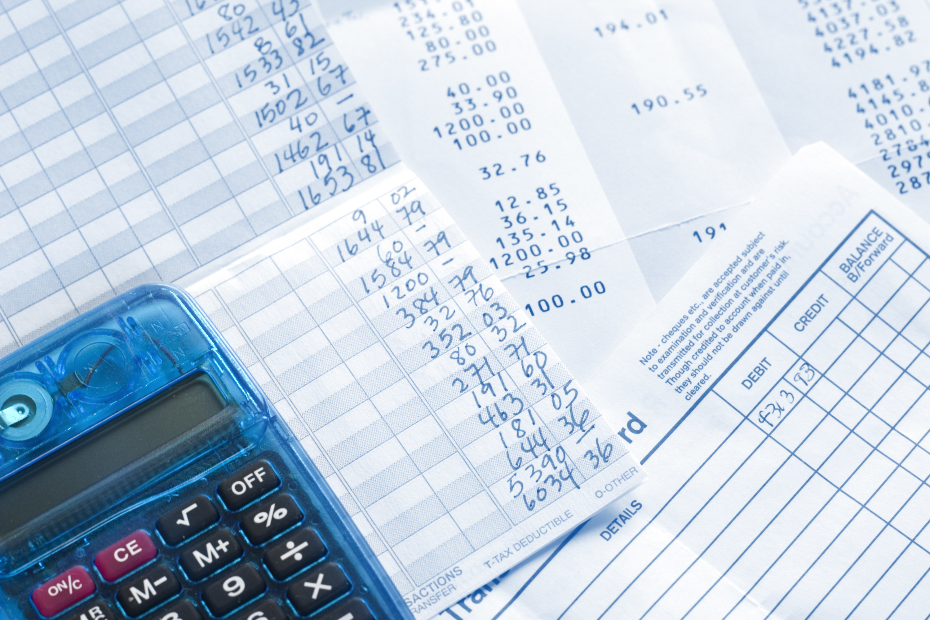 A calculator next to an open checkbook and a serious of receipts 