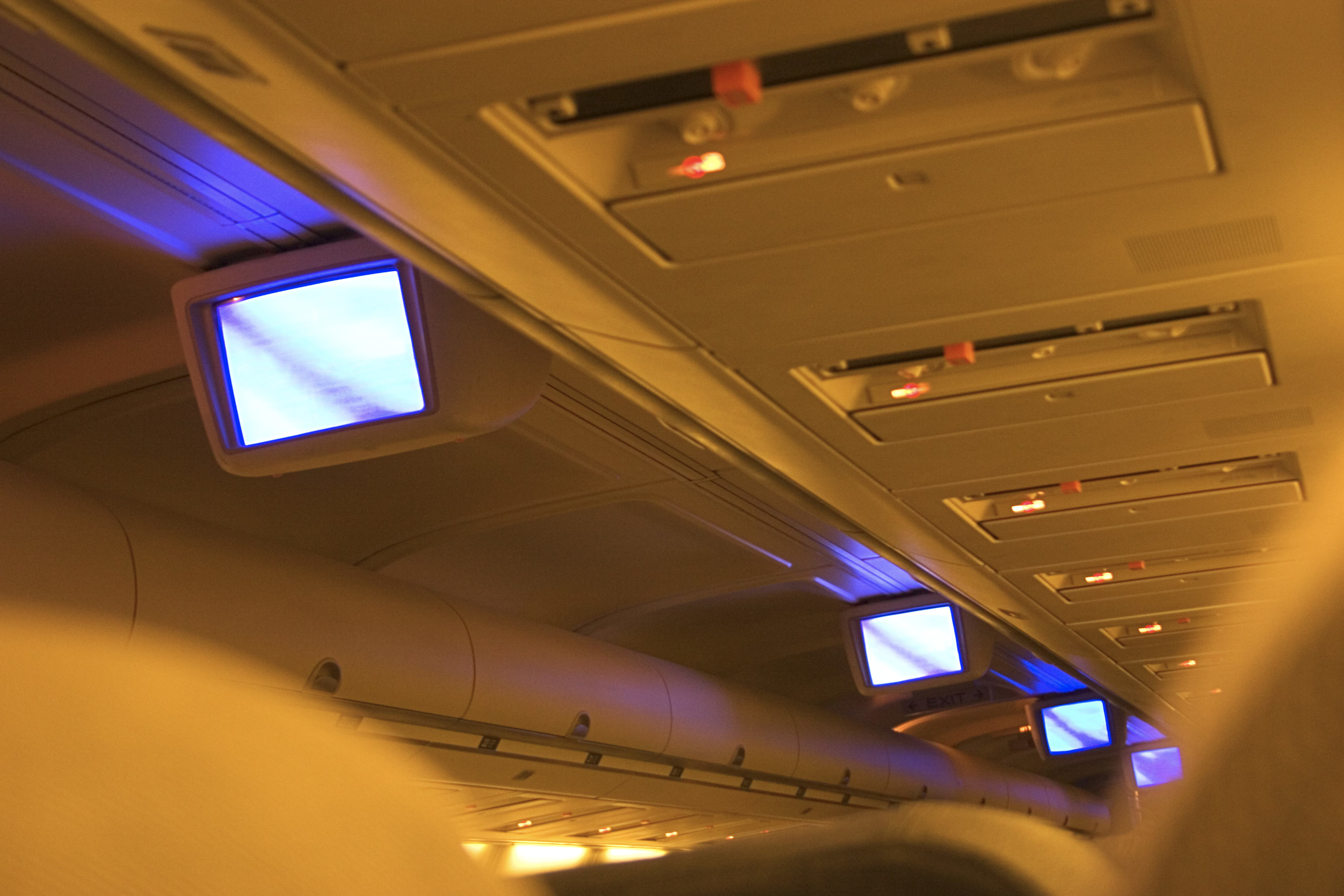 A &#x27;90s plane with TV monitors hanging from the aisle