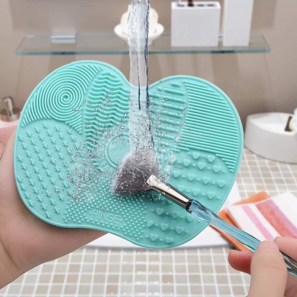 A person scrubbing a brush on the brush-cleaning mat