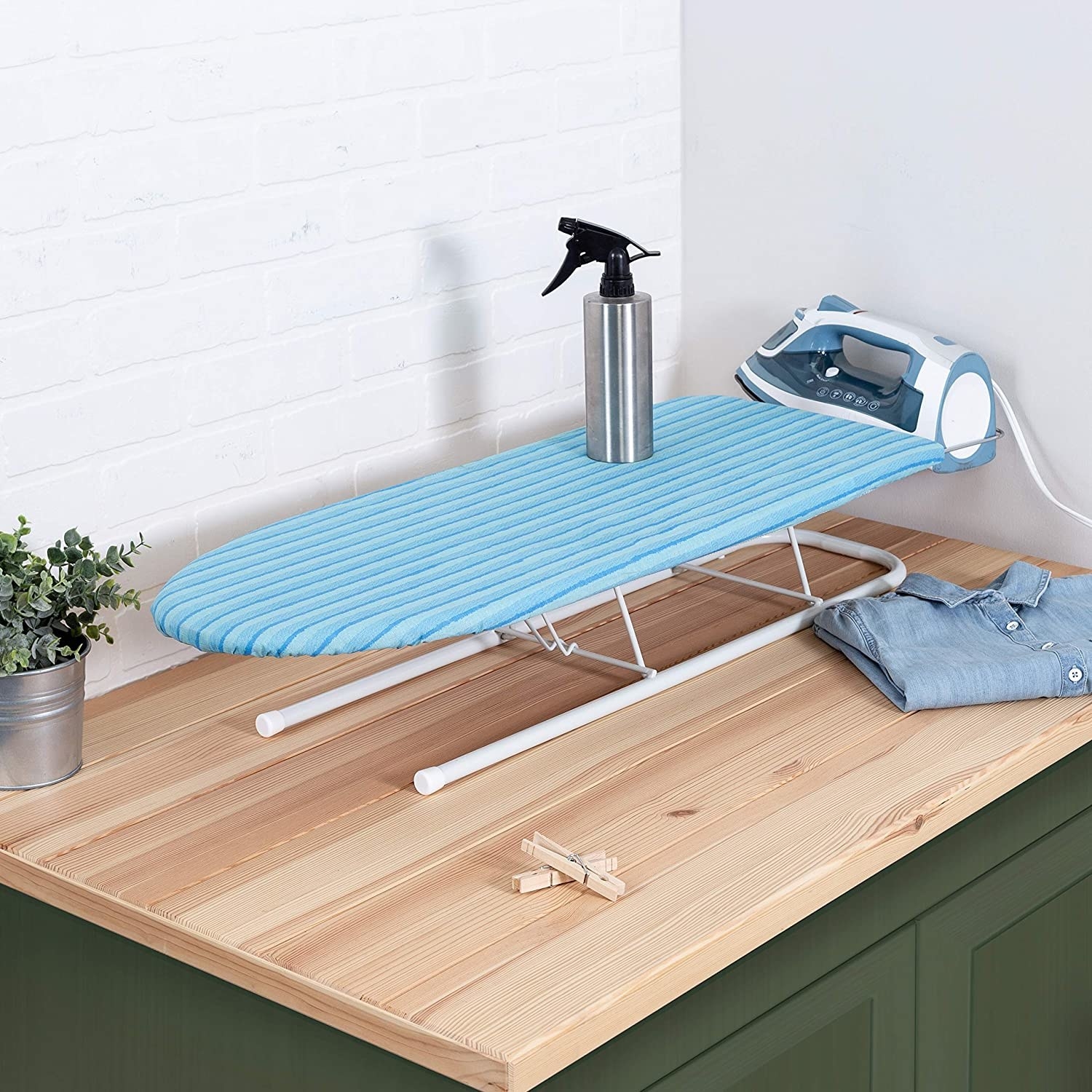 The ironing board on a countertop with a spray bottle on top of it