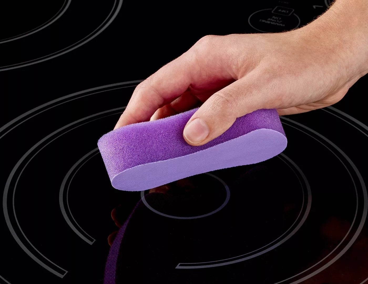 A model using the cleaning pad to clean a glass stovetop