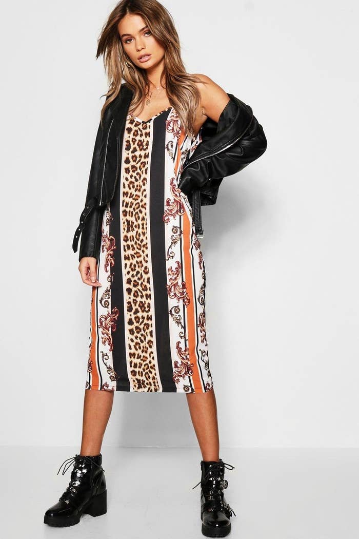 Multi-pattern dress with stripes of animal print, filigree, black, and orange. Worn with black ankle-high boots and leather jacket. 