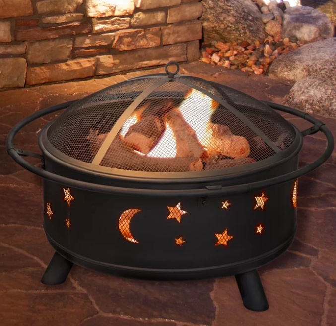 Star and moon-printed black fire pit with burning wood on an outdoor patio