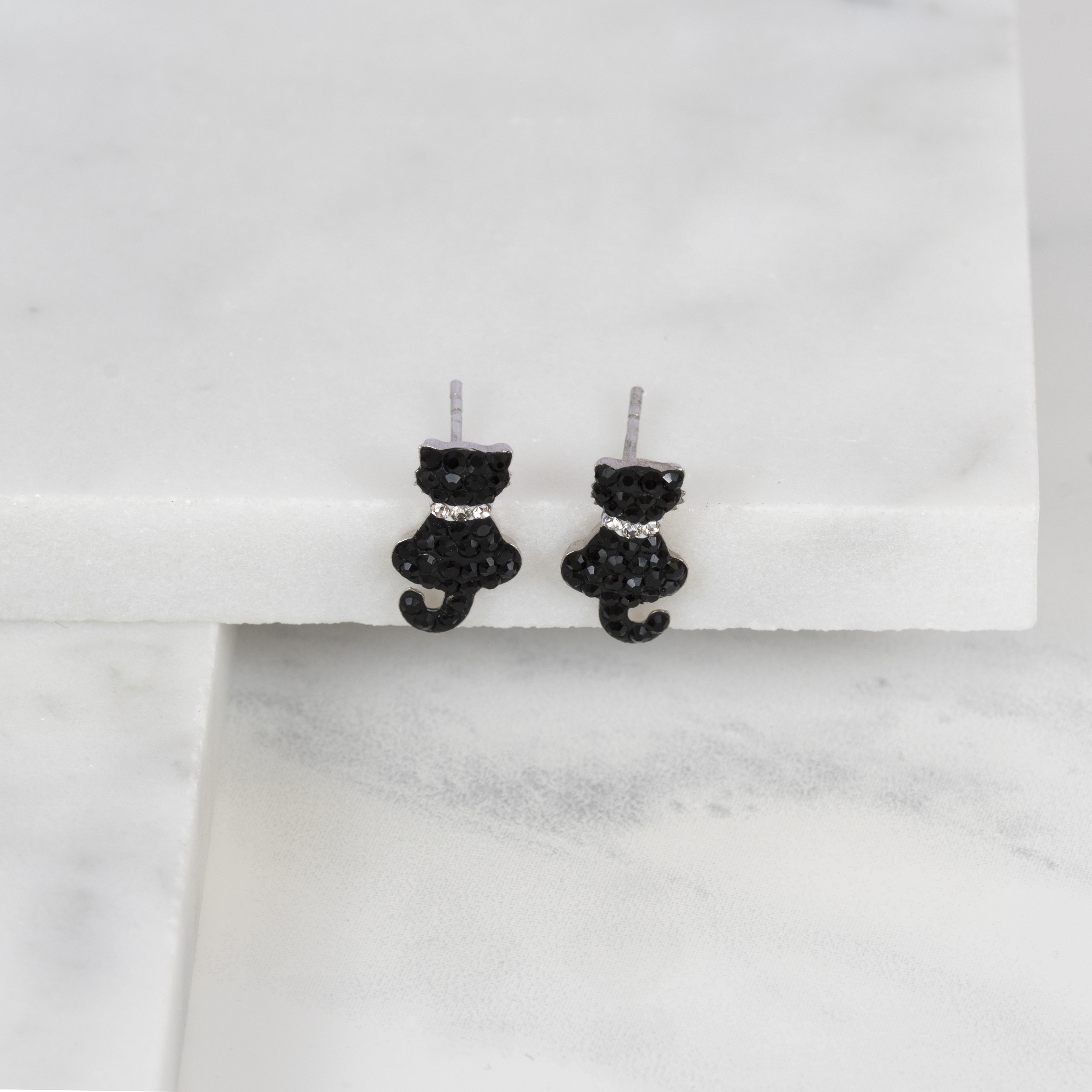 A pair of black and white rhinestone stud earings in the shape of two black cats