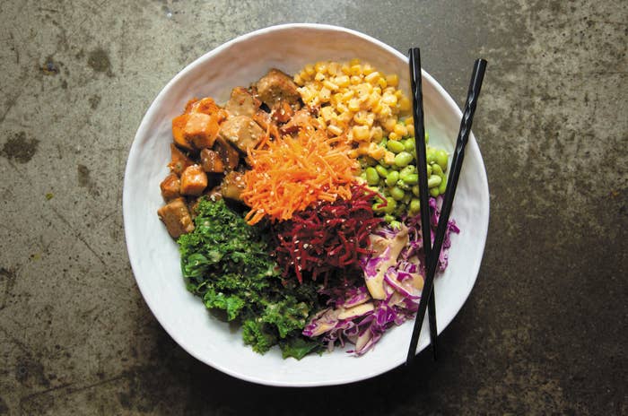 A plate featuring tofu, carrots, beets, cabbage, corn, edamame, and kale.