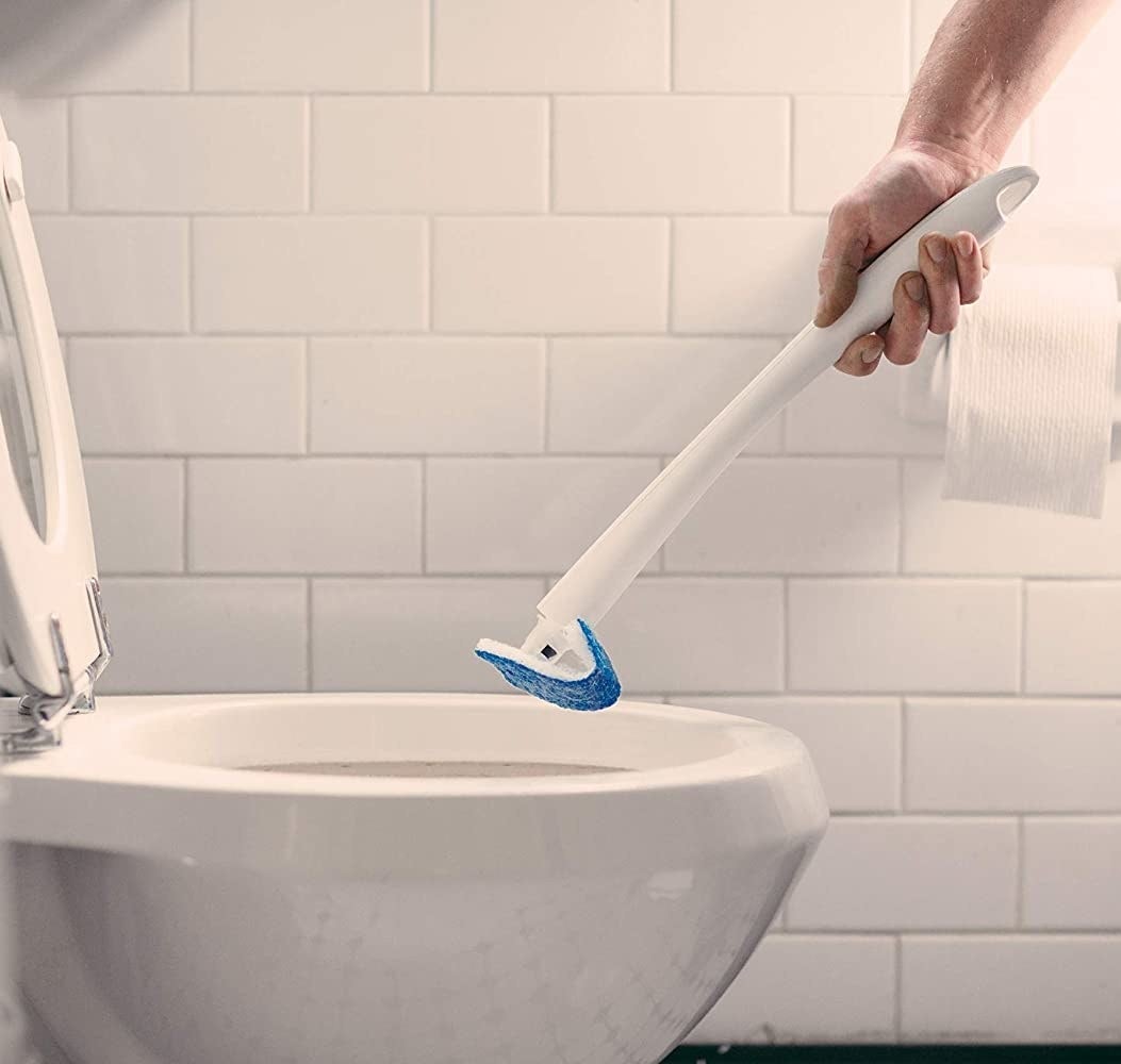 model using white wand brush to clean toilet