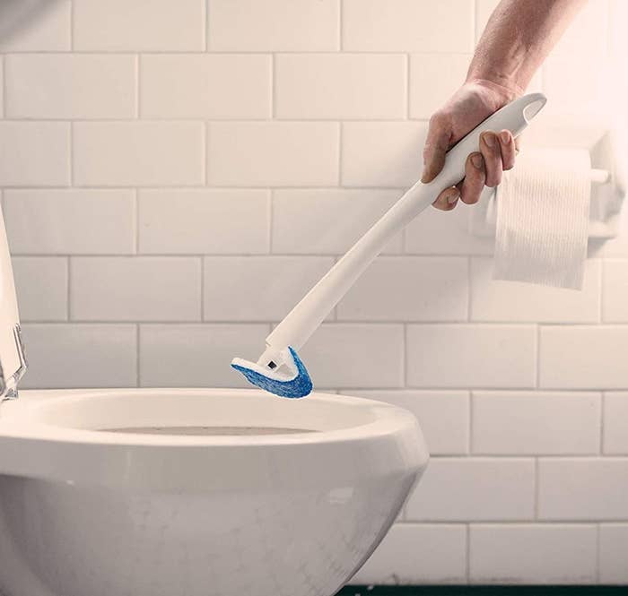 model using white wand brush to clean toilet