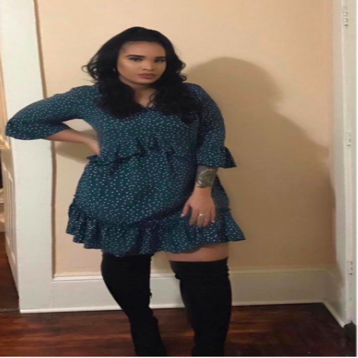 A reviewer wearing the three quarter-sleeve dress in teal with white polka dots with black thigh-high boots