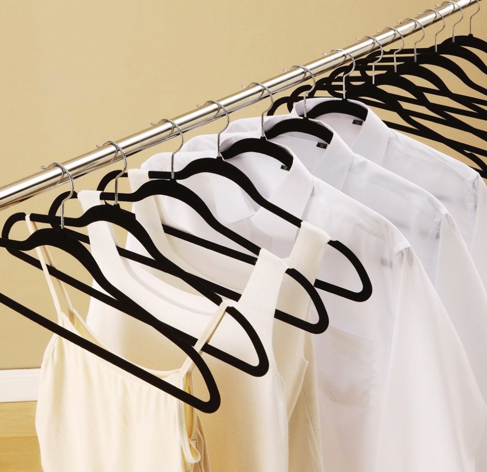 The black hangers holding white collared shirts and tank tops