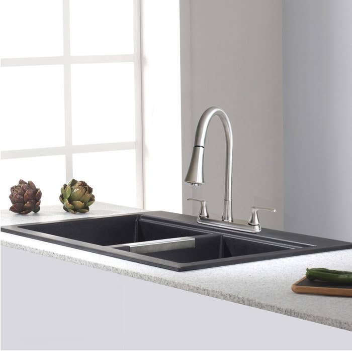 A brushed nickel kitchen faucet with a pull-down spray installed on a sink in a kitchen
