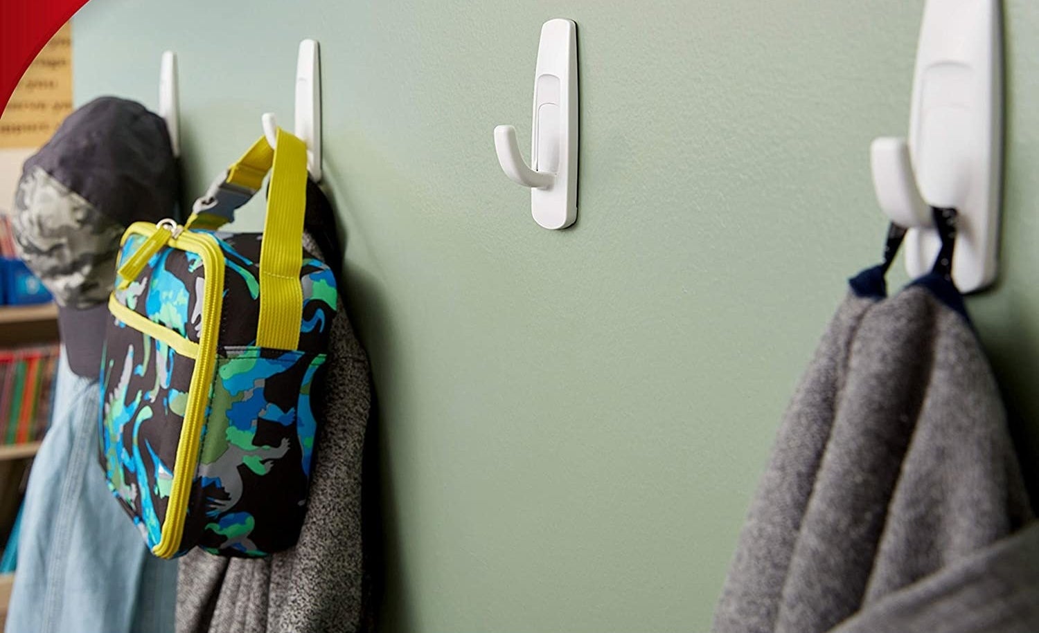 White Command hooks on a wall holding hats, lunch bags, and shirts