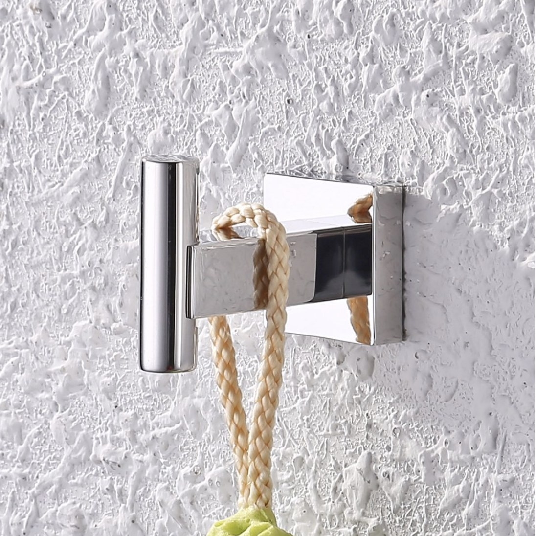 A chrome wall hook installed to a wall holding with a loofah hanging off of it
