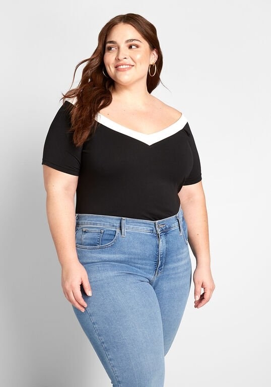 A model wearing the black short sleeve top with a white border around the V-neckline