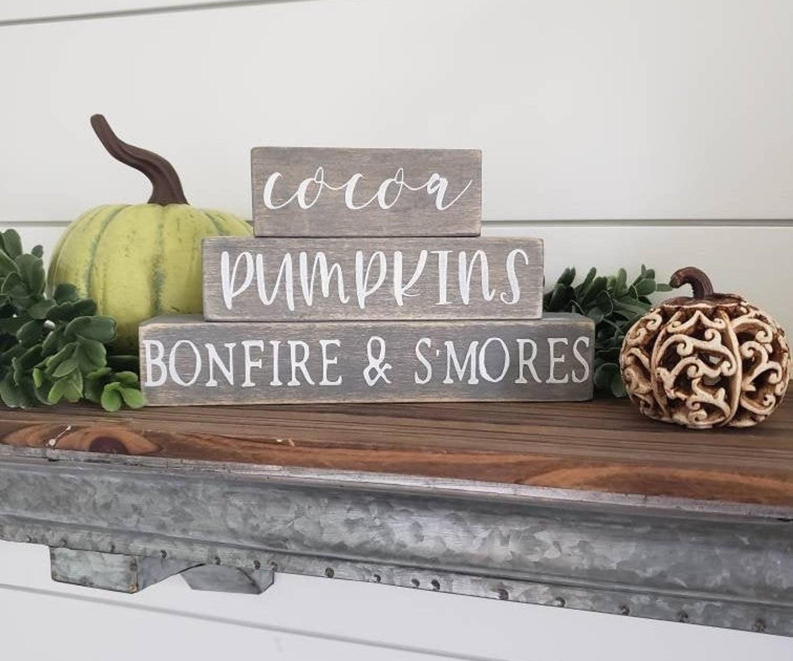 Three gray wooden signs that read &quot;cocoa&quot;, &quot;pumpkins&quot; and &quot;bonfire &amp;amp; s&#x27;mores&quot; 