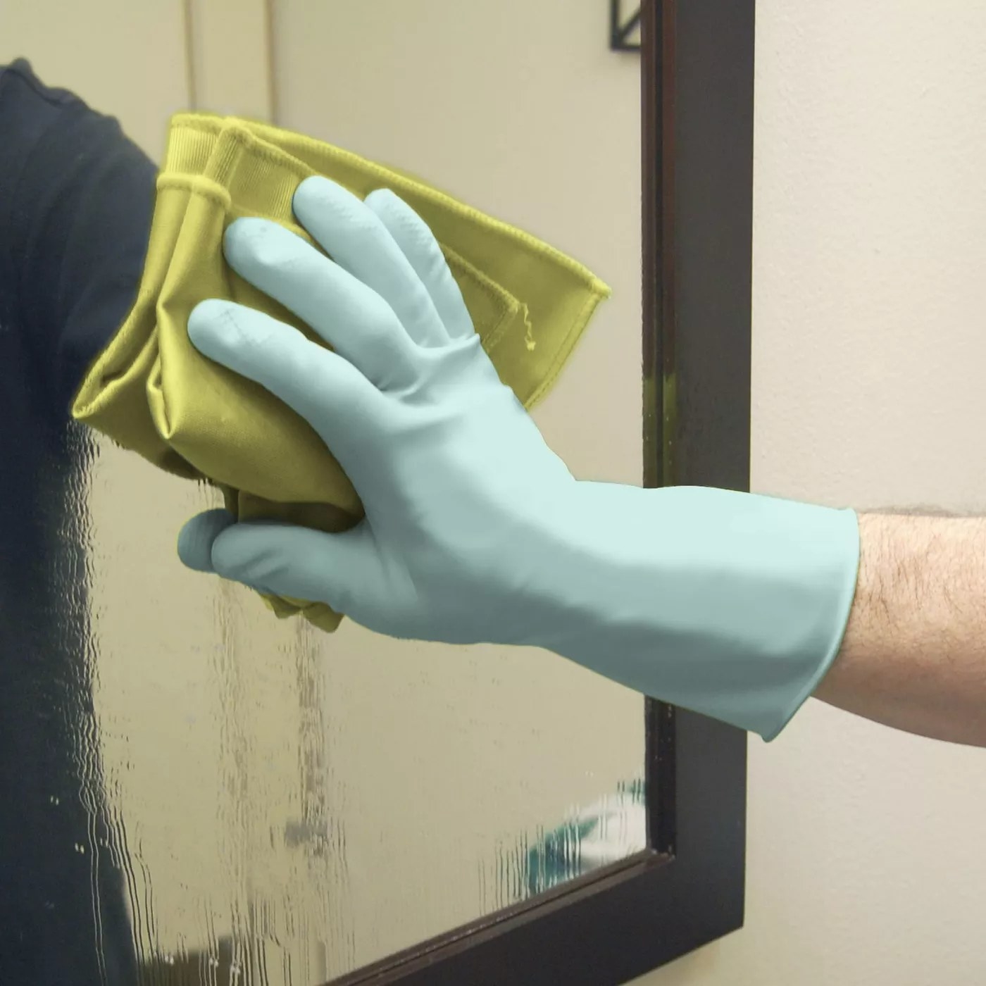 A model wearing a pair of light blue gloves wiping down a mirror