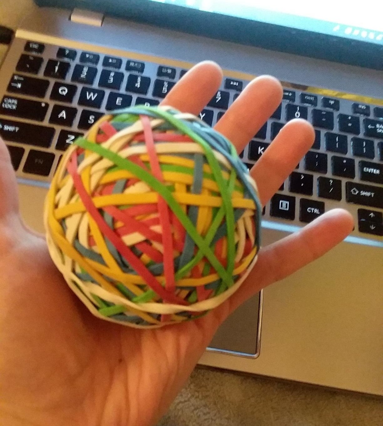 Reviewer&#x27;s hand holding a colorful ball of rubber bands 