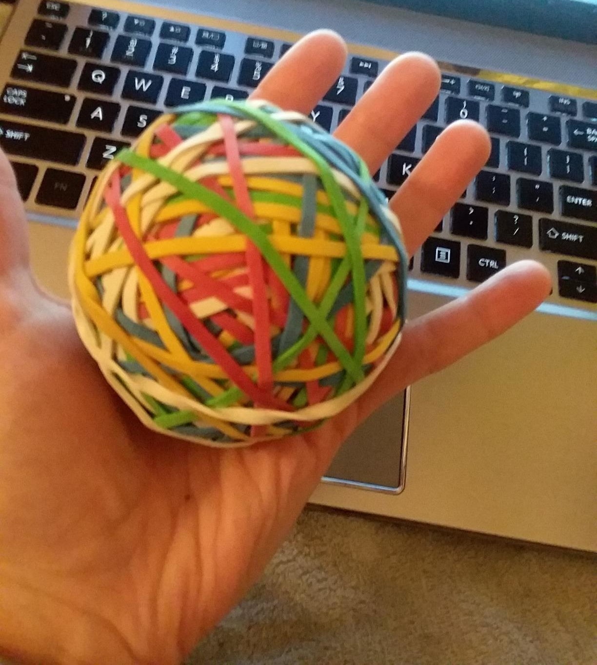 Reviewer's hand holding a colorful ball of rubber bands