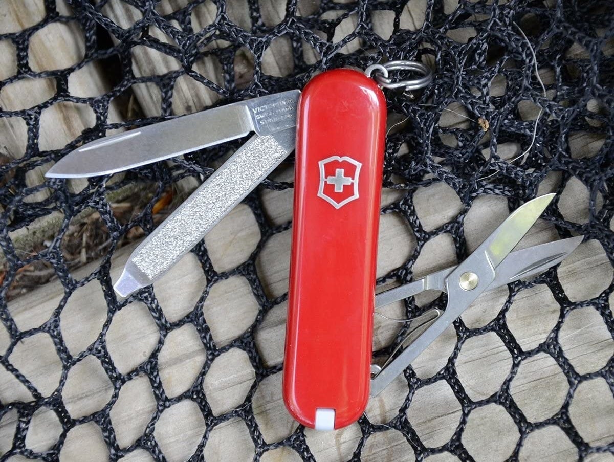 A red Swiss Army knife with scissors, a blade, and a file