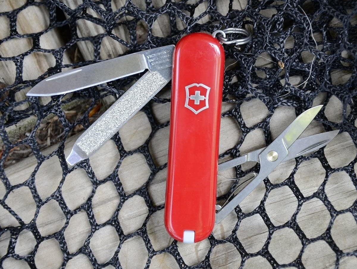 A red Swiss Army knife with scissors, a blade, and a file