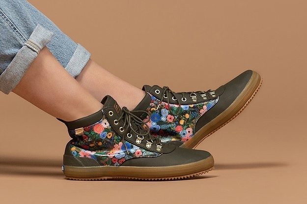 a model in green rubberized boots with rifle paper floral accents