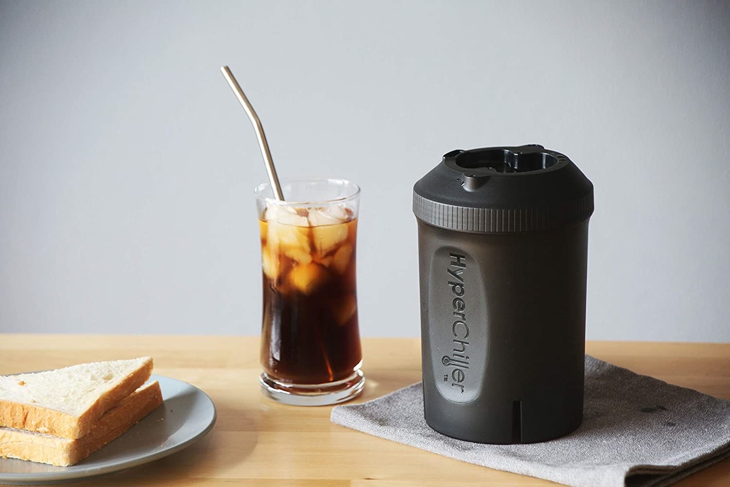 The beverage chiller next to a glass of iced coffee on a butcher block counter