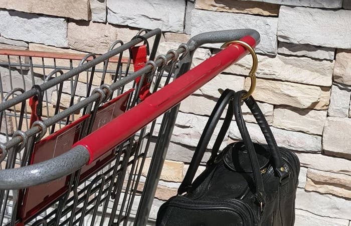 A purse hangs by a gadget on a shopping cart