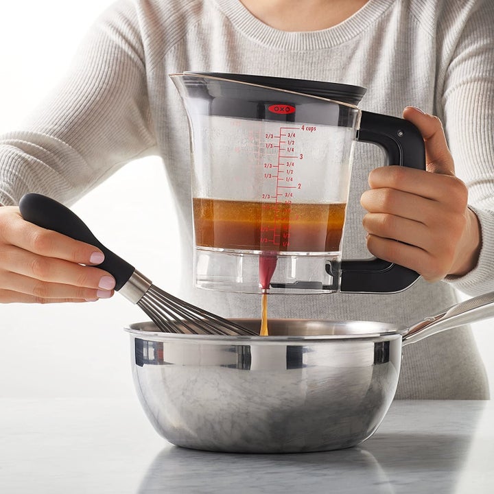A person uses the separator to pour gravy into a bowl
