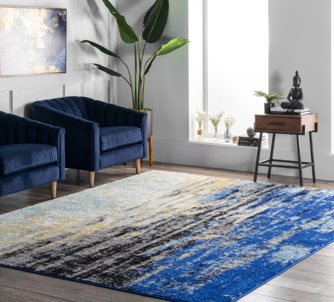 Abstract blue waterfall-print rug next to dark blue velvet armchairs