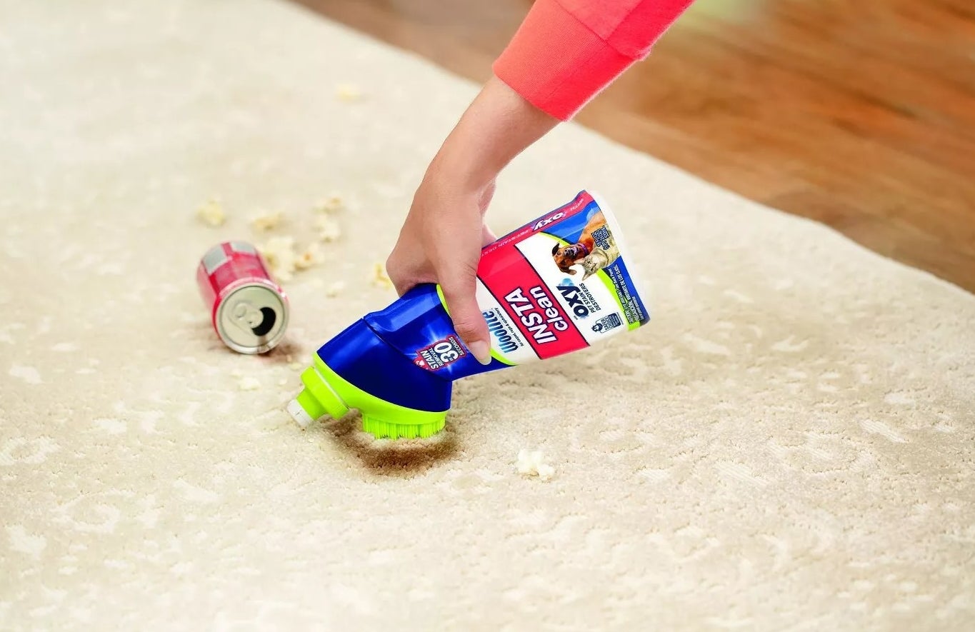 A model using Woolite's Insta-Clean stain remover to scrub a soda spill off of a rug