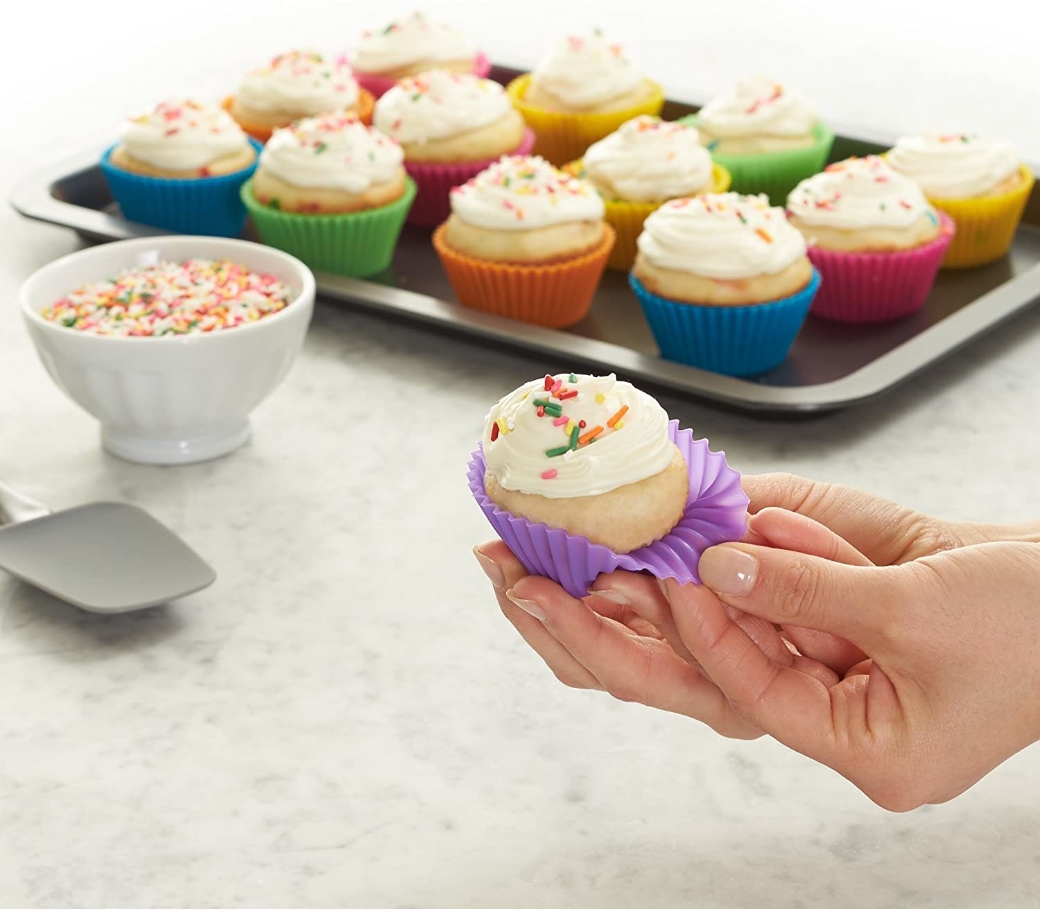 A person pulling a silicone muffin cup off a small cupcake