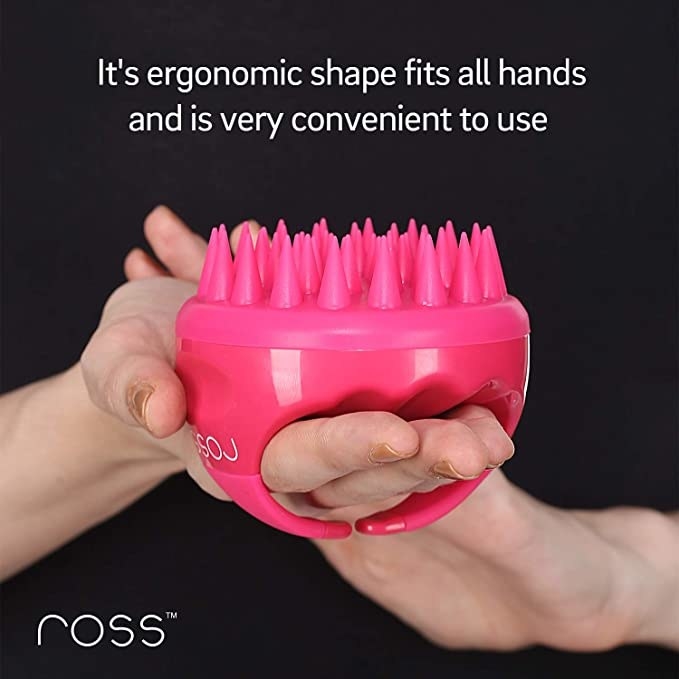 Person holding the pink shampoo brush in their hands.