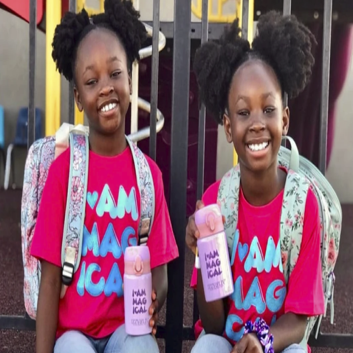 two children with backpacks on each holding the pink version of the cup.