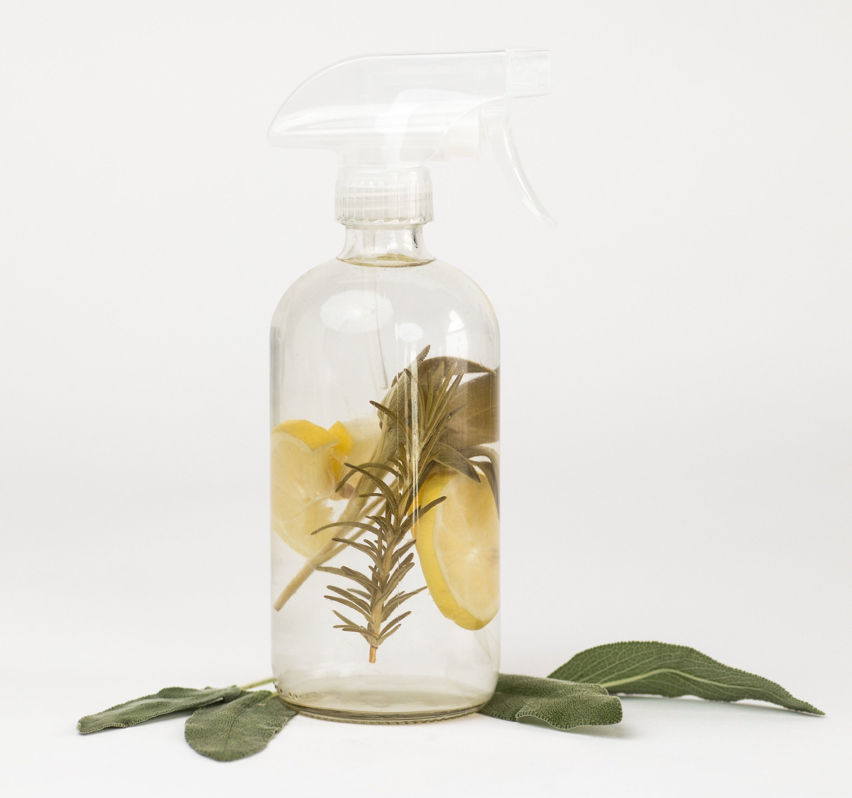 The clear bottle of cleaner with rosemary and lemon it 