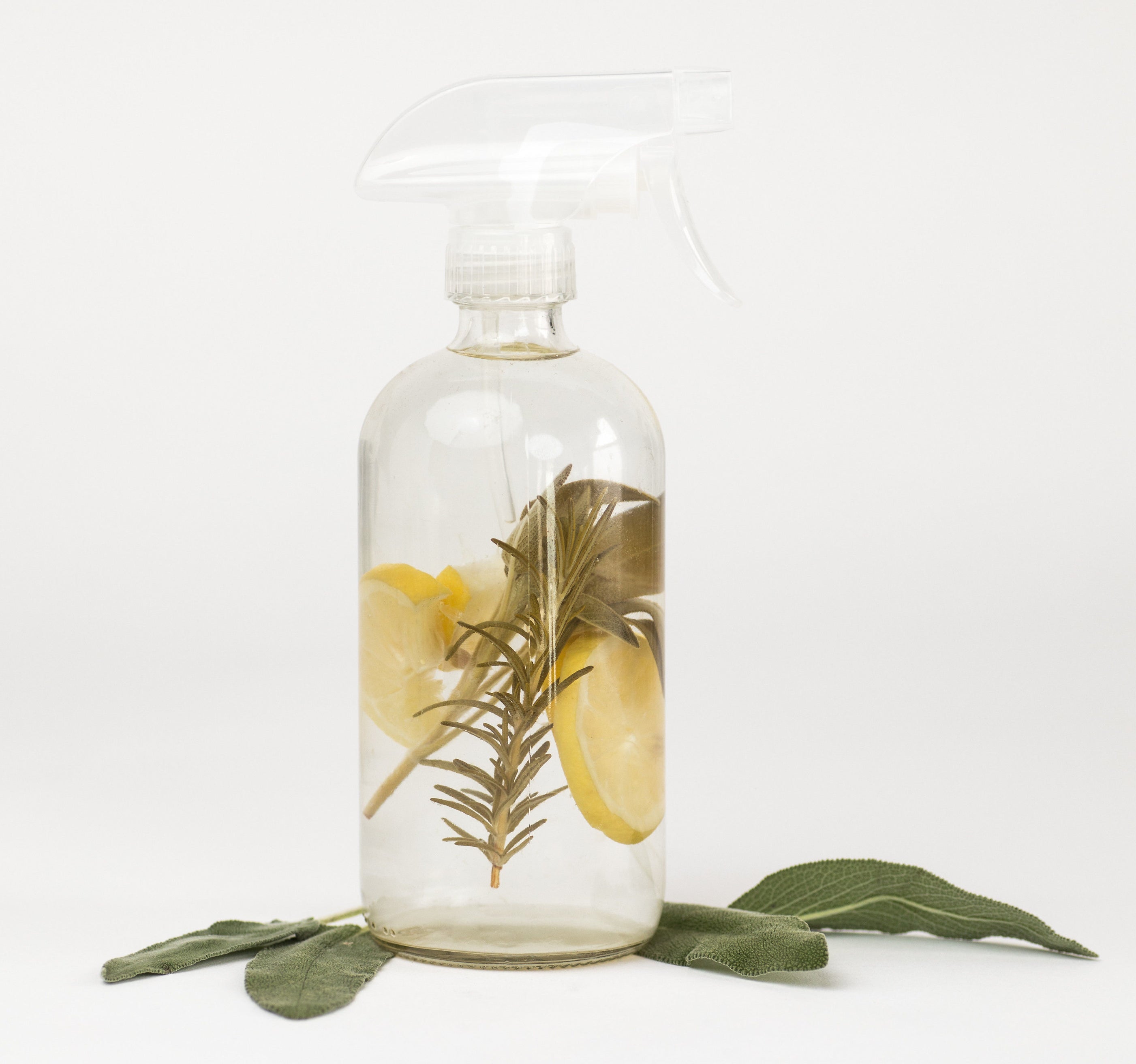The clear bottle of cleaner with rosemary and lemon it 