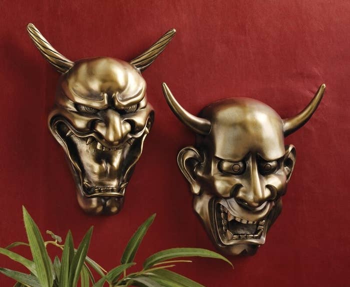 The twin masks hung side by side on a red wall
