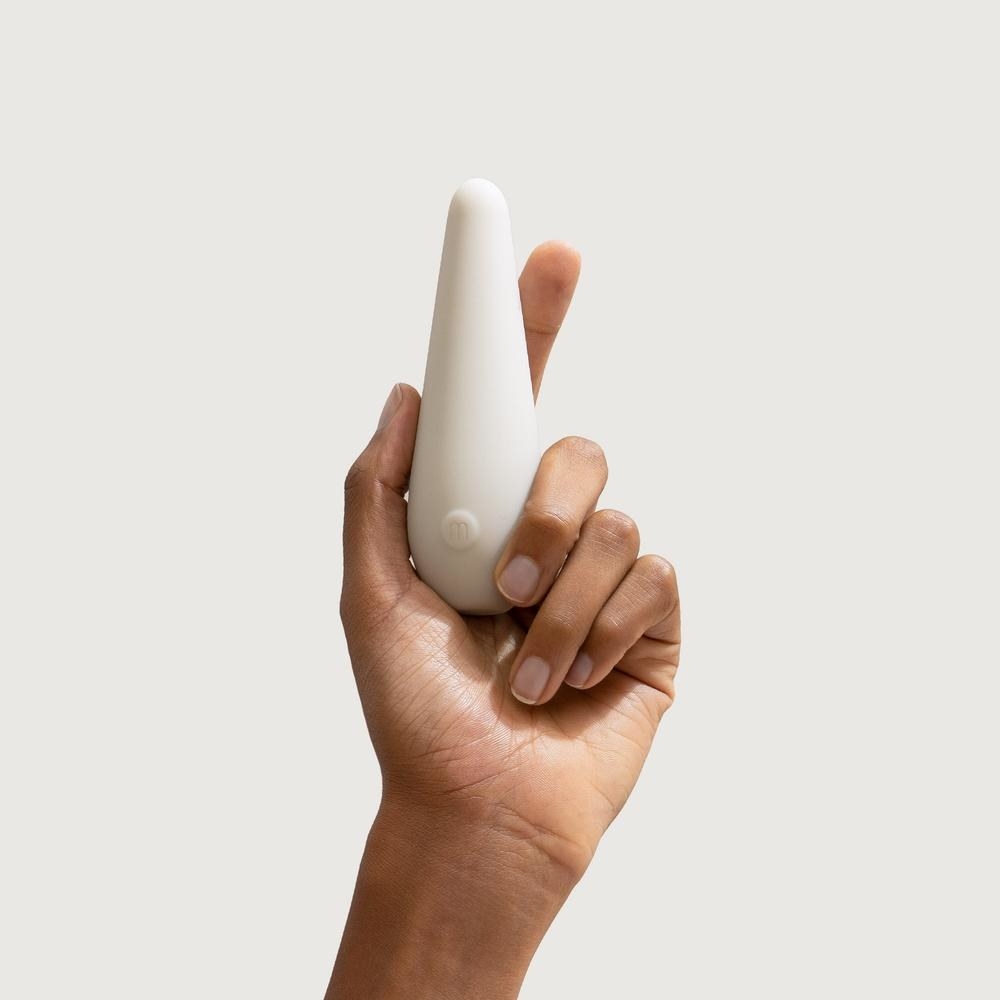 Hand holding the white elongated vibe with a tapered point and single control button