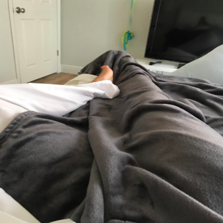 a reviewer's photo of their legs under a blanket and the sheets