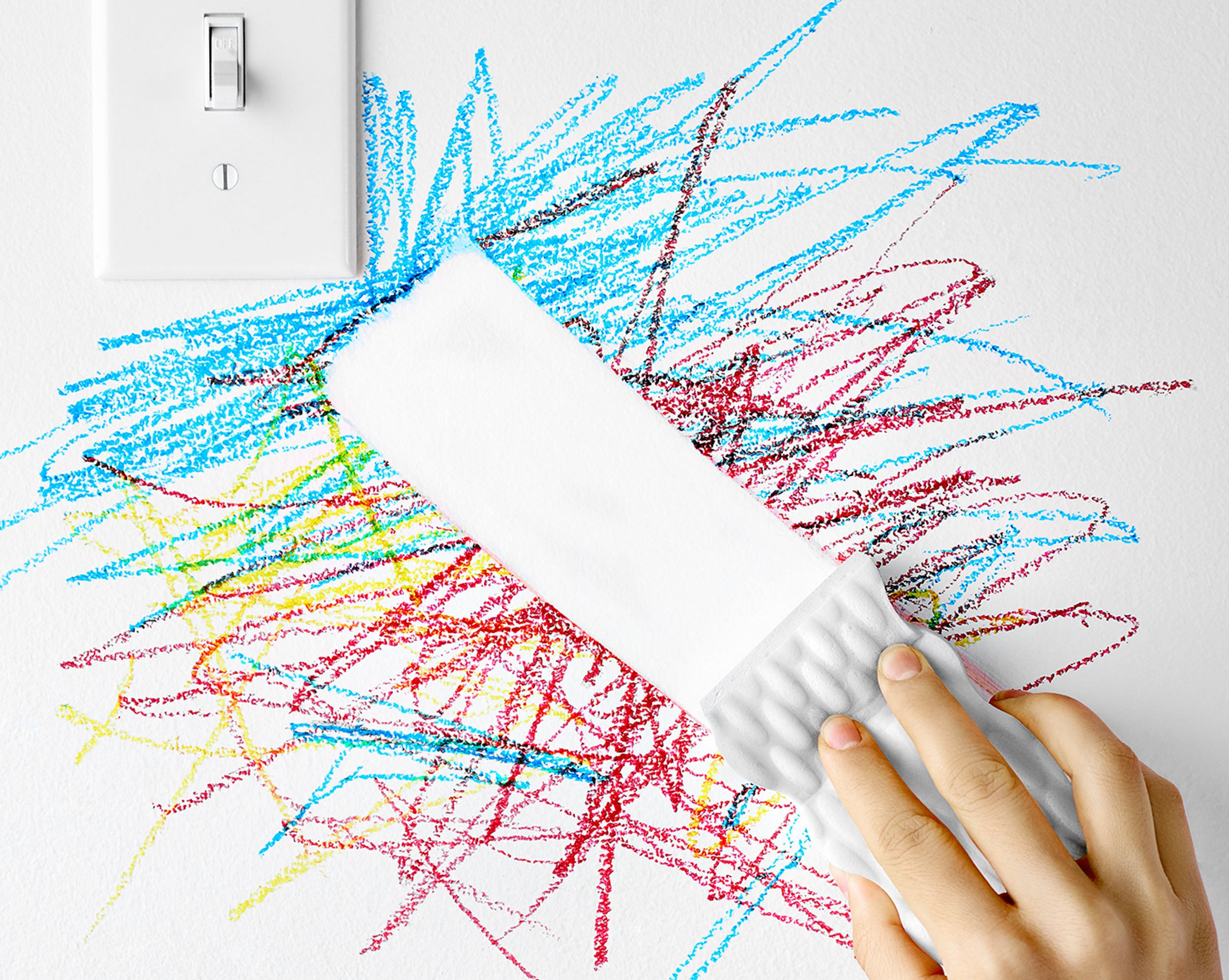 person using mr. clean magic eraser to remove crayon marks from a wall