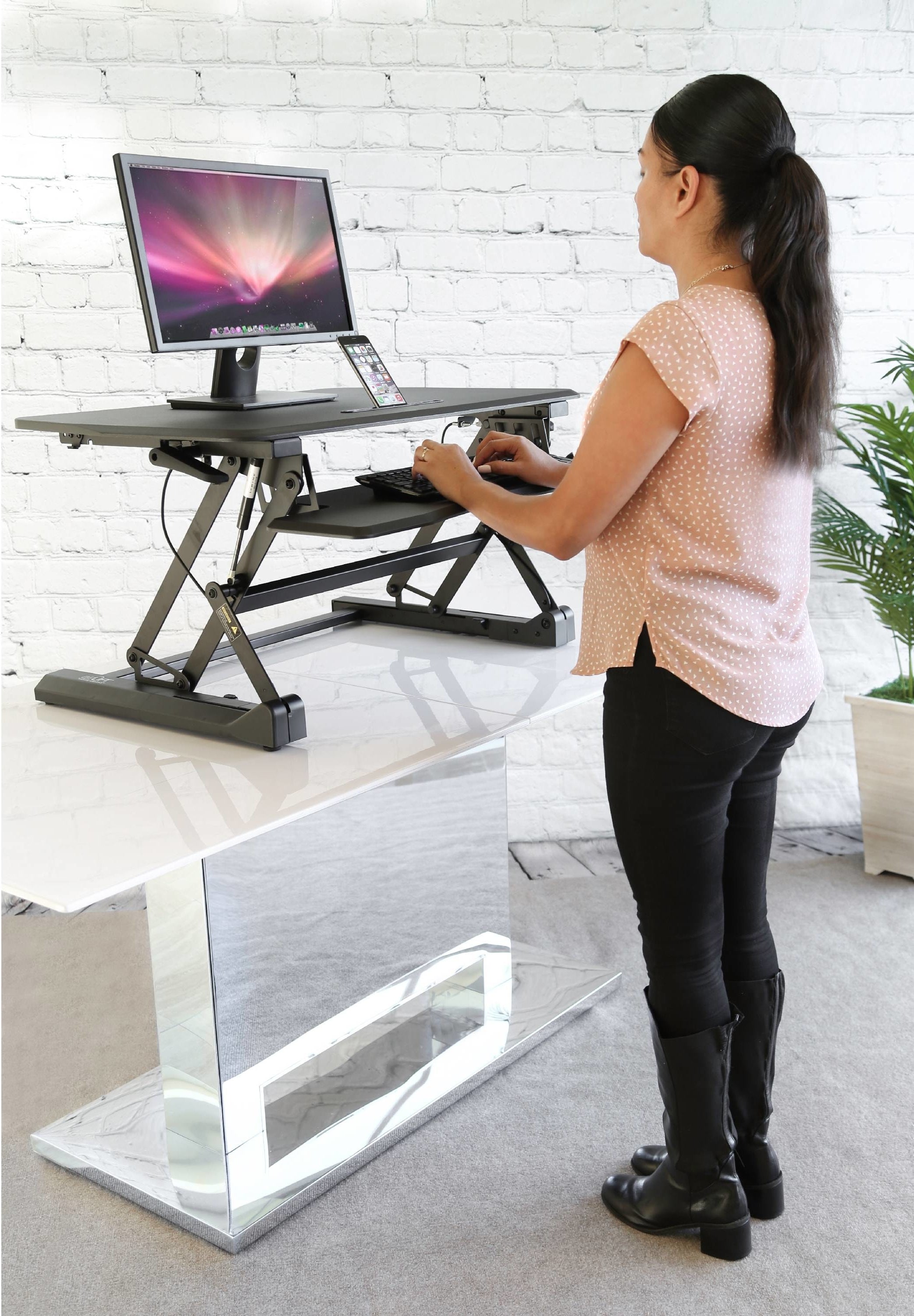 person typing on a keyboard as they are standing at a standing desk