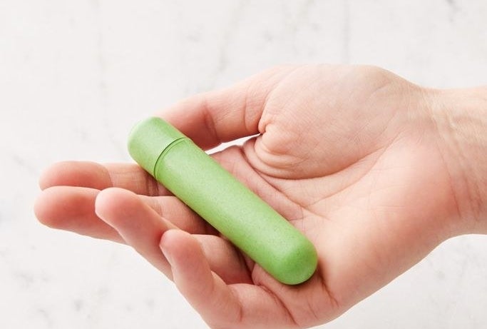 Hand holding the green, lipstick-size vibrator