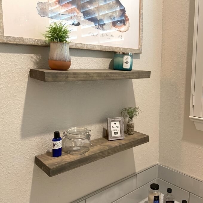 Reviewer&#x27;s picture of the two wooden floating shelves in their bathroom 