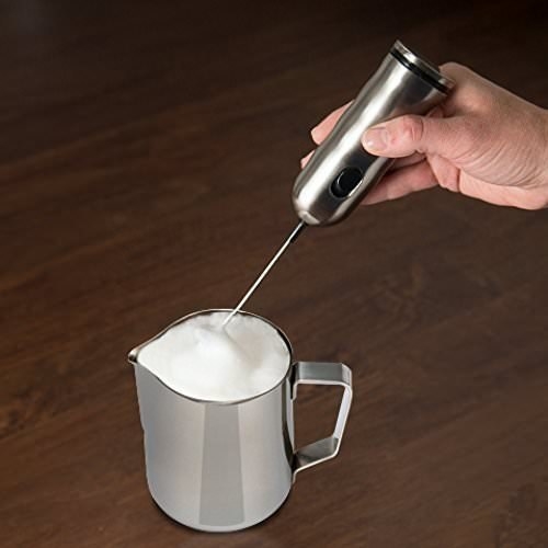 Person frothing milk in the pitcher with an electrical frother.