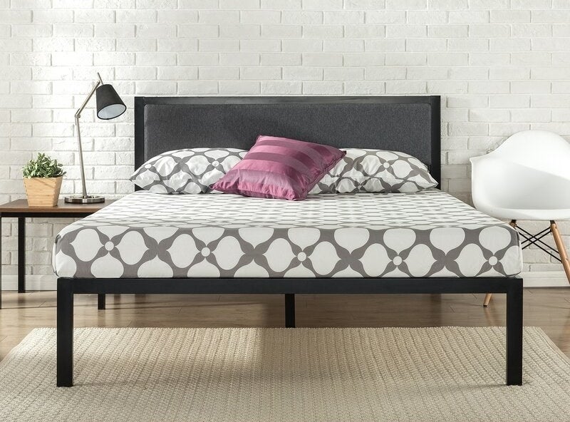 A black bed frame with gray upholstered headboard filled with foam