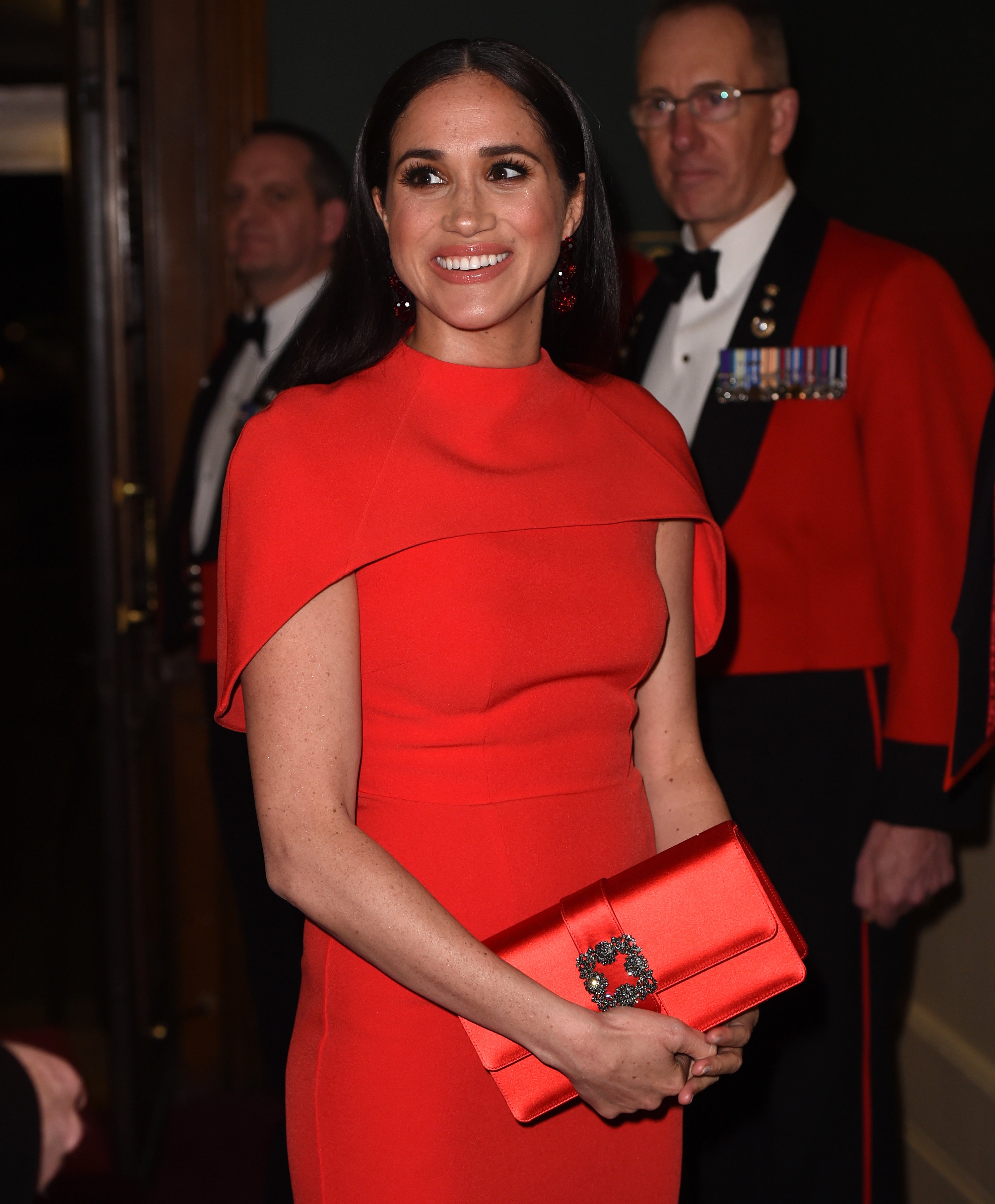 Meghan Markle smiling in a red dress