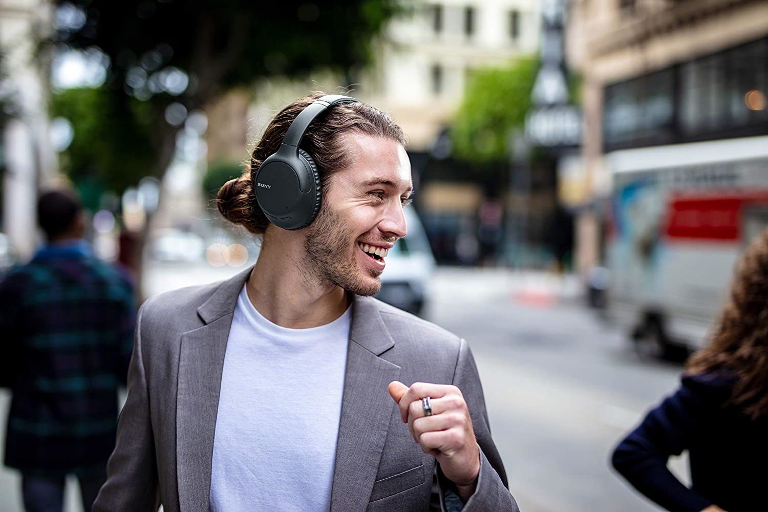 A person walking down the street with a pair of over-ear headphones on