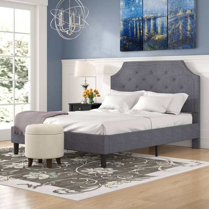 Gray bed frame with upholstered tufted headboard and nailhead trim